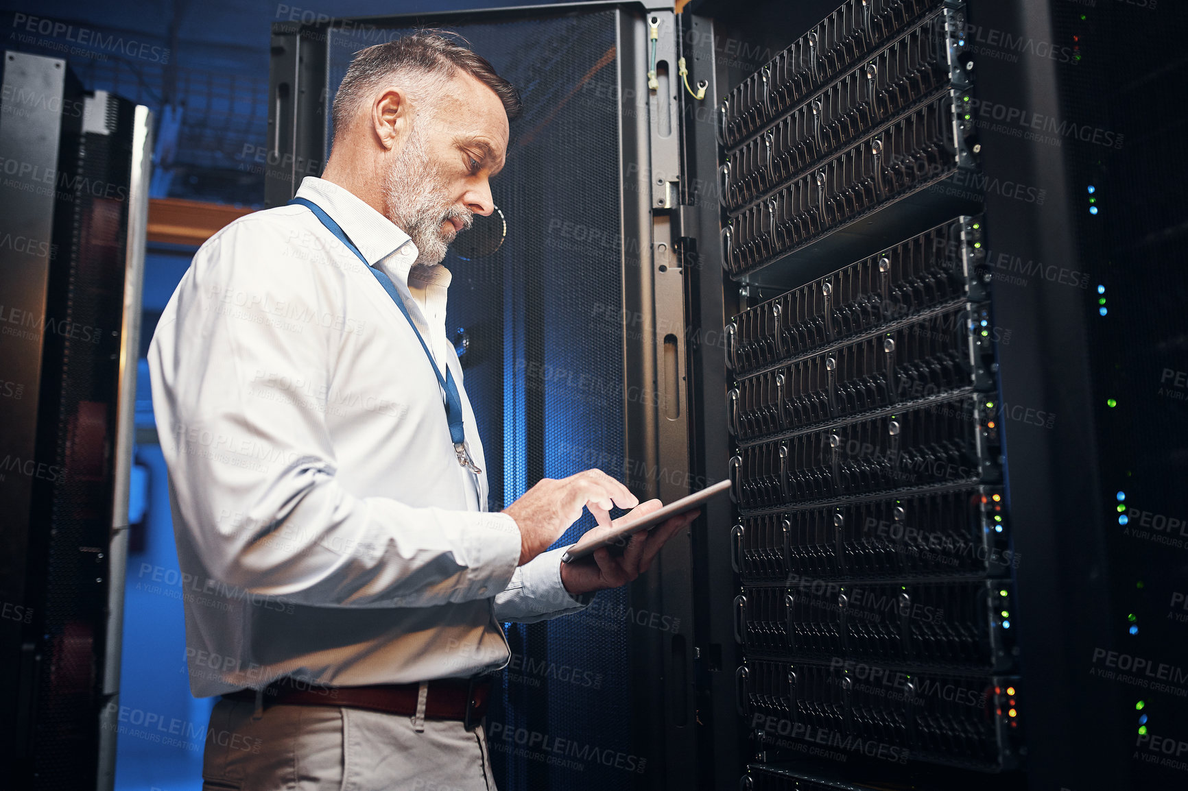 Buy stock photo Shot of a mature man using a digital tablet while working in a server room