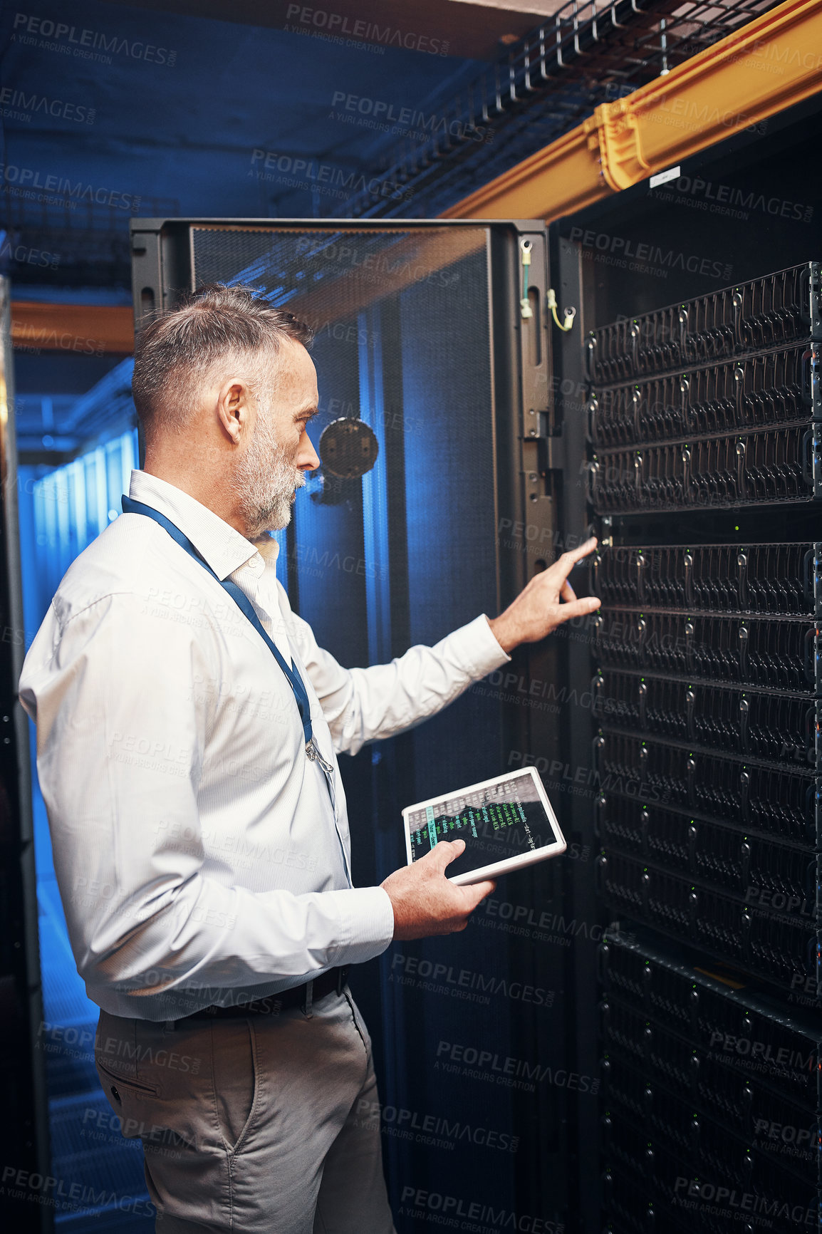 Buy stock photo Shot of a mature man using a digital tablet while working in a server room