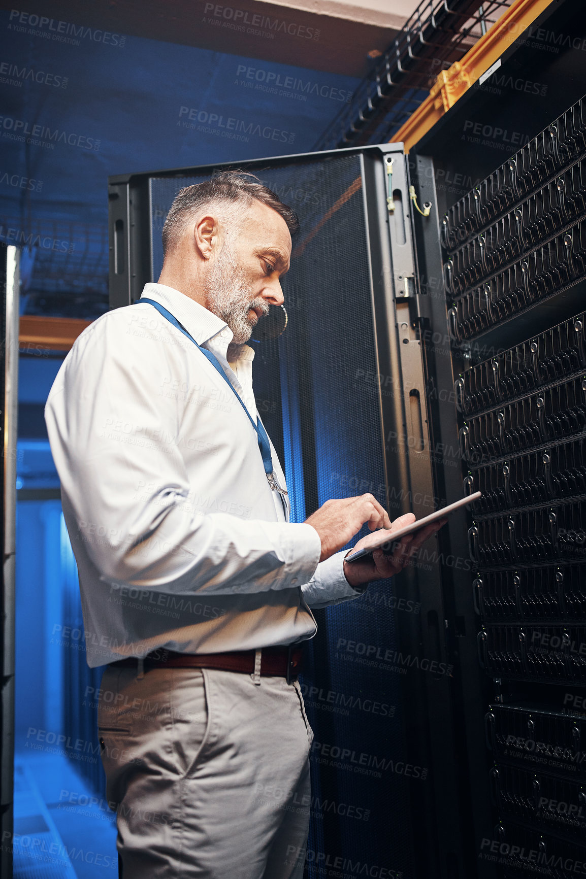 Buy stock photo Shot of a mature man using a digital tablet while working in a server room