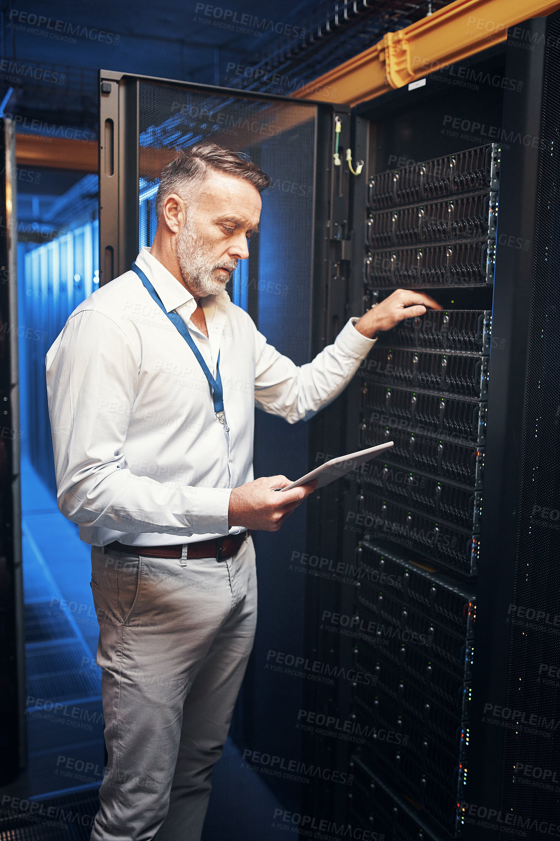 Buy stock photo Shot of a mature man using a digital tablet while working in a server room