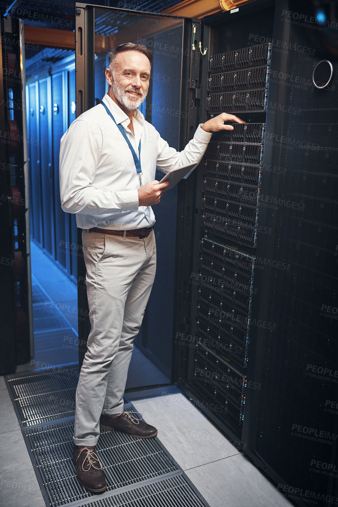 Buy stock photo Shot of a mature man using a digital tablet while working in a server room