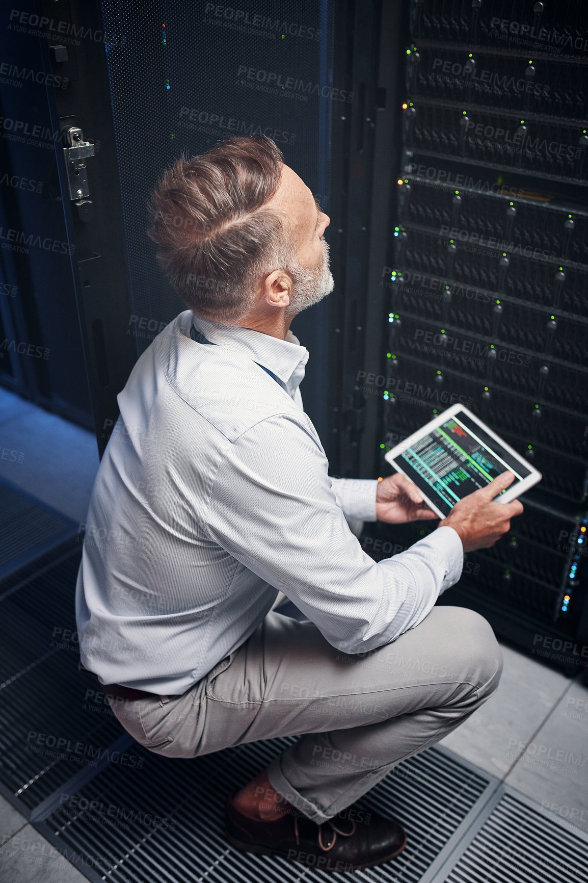 Buy stock photo Shot of a mature man using a digital tablet while working in a server room