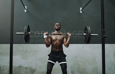 Buy stock photo Shot of a muscular young man doing an overhead press with a barbell in a gym