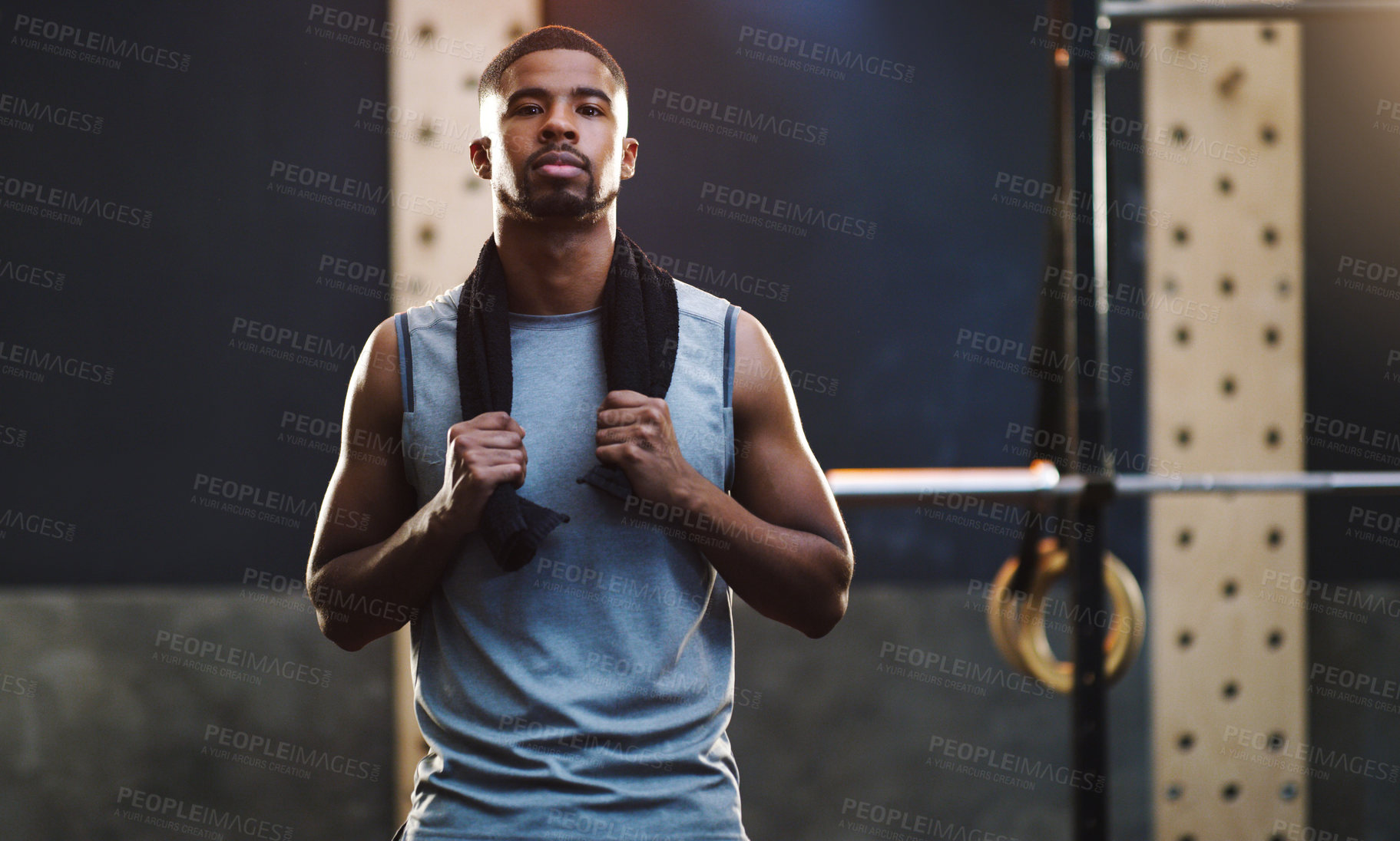 Buy stock photo Portrait of a muscular young man standing with a towel around his neck in a gym