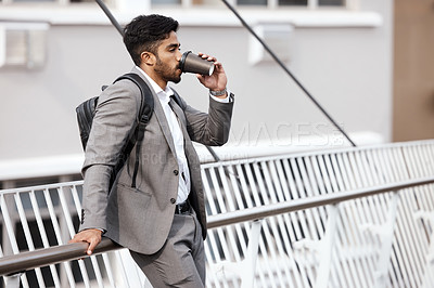 Buy stock photo Shot of a young businessman drinking a cup of coffee in the city