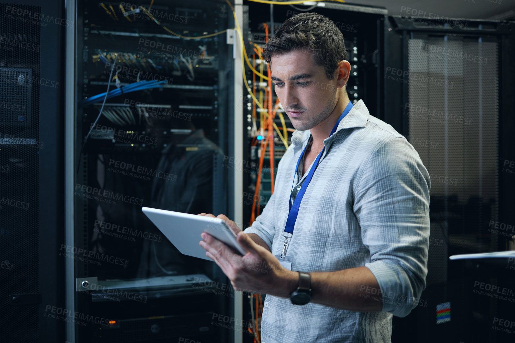 Buy stock photo Cropped shot of a handsome young male programmer working on a tablet in a server room