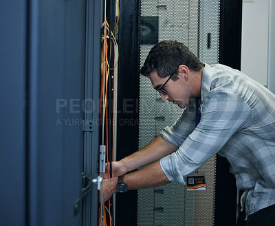 Buy stock photo Cropped shot of a handsome young male programmer working in a server room