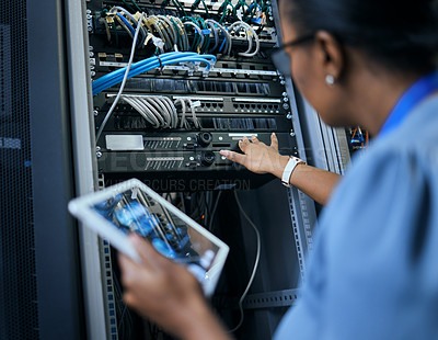 Buy stock photo Rearview shot of an unrecognizable female programmer working on a tablet in a server room
