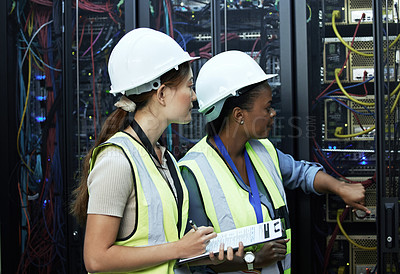 Buy stock photo Cropped shot of two attractive female programmers working in a server room