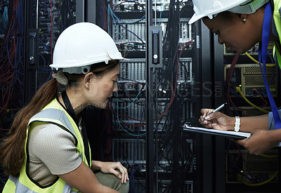 Buy stock photo Cropped shot of two attractive female programmers working in a server room