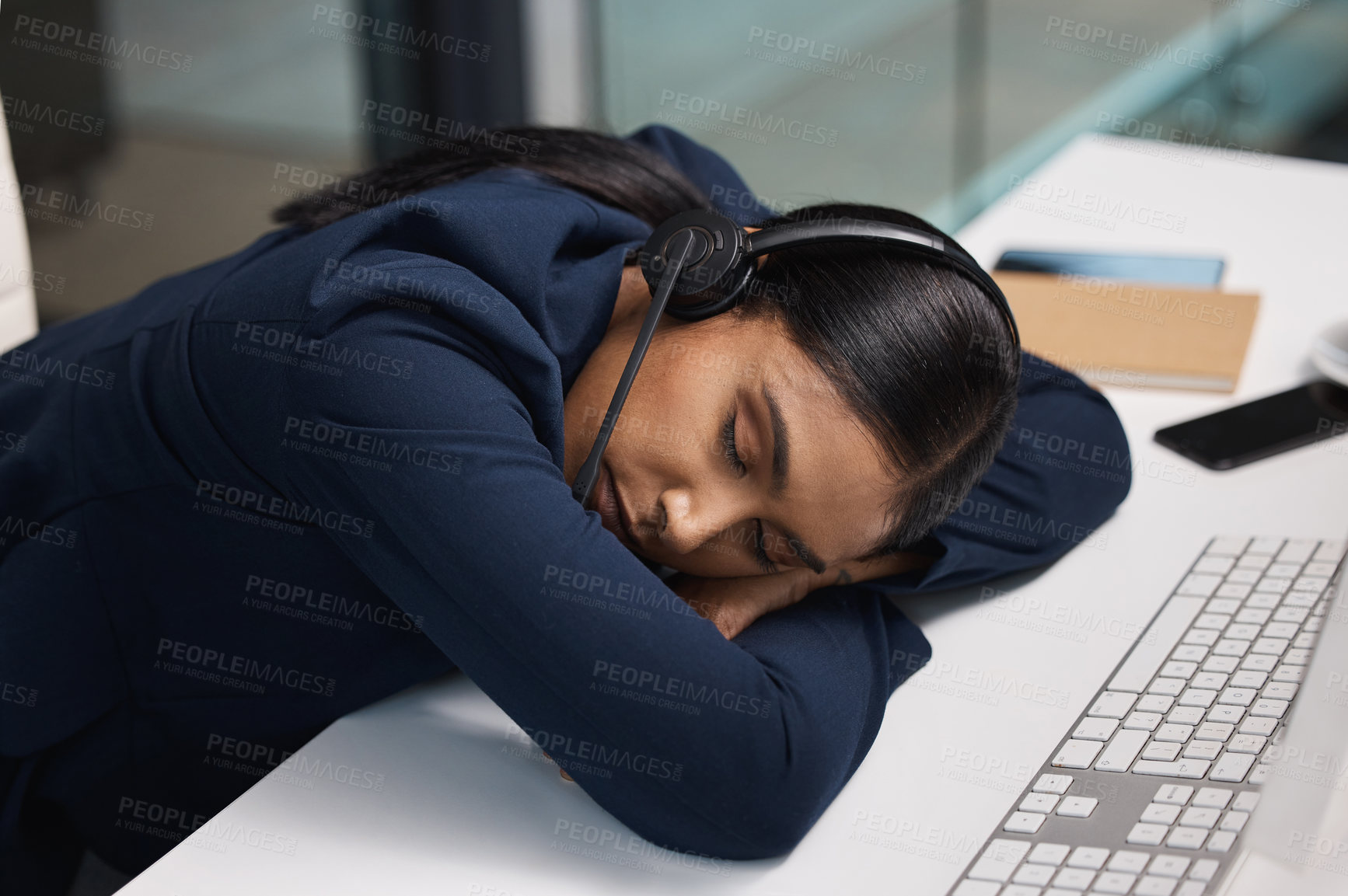 Buy stock photo Shot of a young businesswoman sleeping at her desk in a call centre