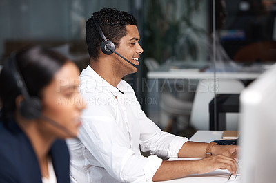 Buy stock photo Shot of a young businessman working on a computer in a call centre