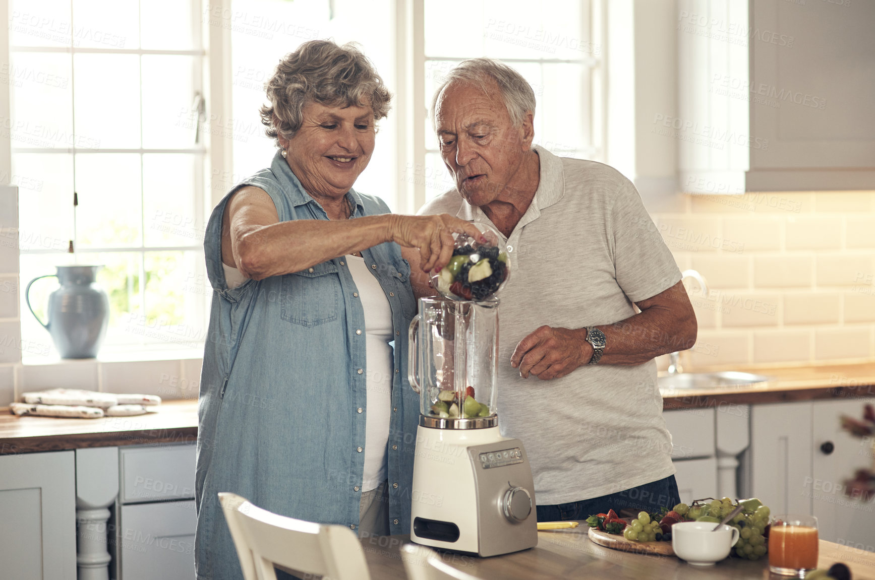 Buy stock photo Shot of a senior couple making a smoothie in the kitchen at home
