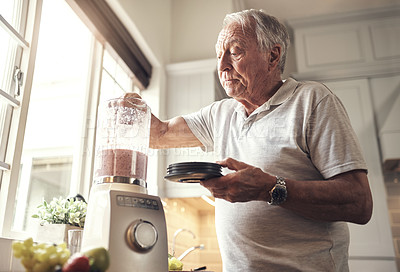 Buy stock photo Shot of a senior man making a smoothie in the kitchen at home