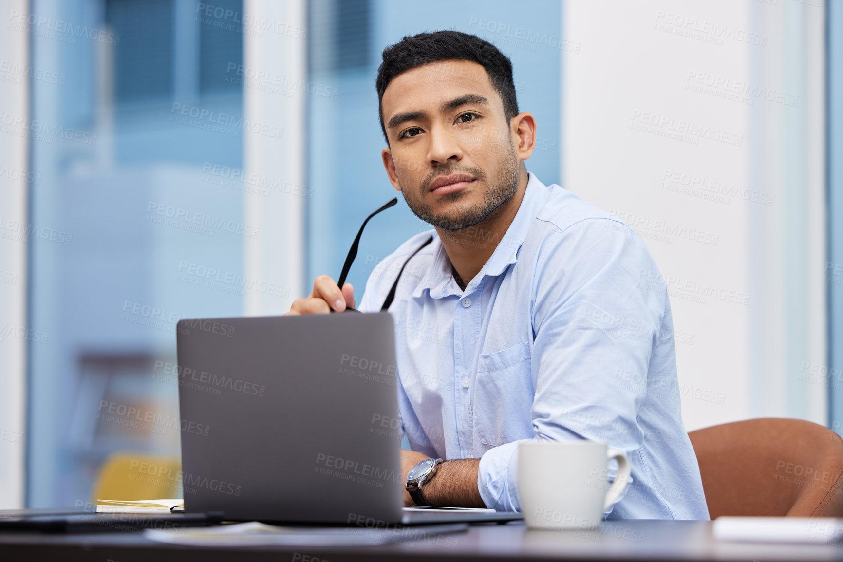 Buy stock photo Shot of a handsome young businessman sitting alone in his office and using his laptop