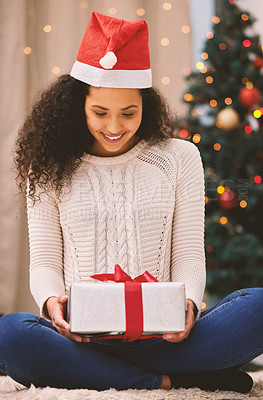 Buy stock photo Shot of a happy young woman opening presents during Christmas at home