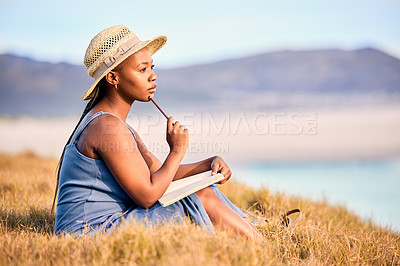 Buy stock photo Shot of a young woman writing in her journal at the beach