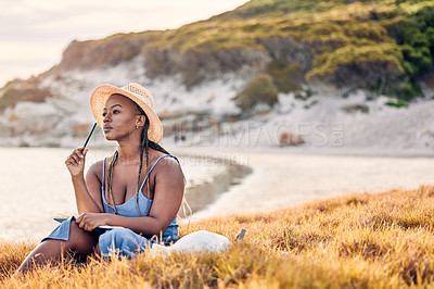 Buy stock photo Shot of a young woman writing in her journal at the beach