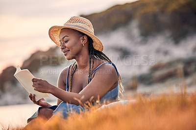 Buy stock photo Nature, mountain and woman reading a book while relaxing outdoor on the grass at sunset in summer. Freedom, travel and calm African female person enjoying a novel or fantasy story on hill with peace.