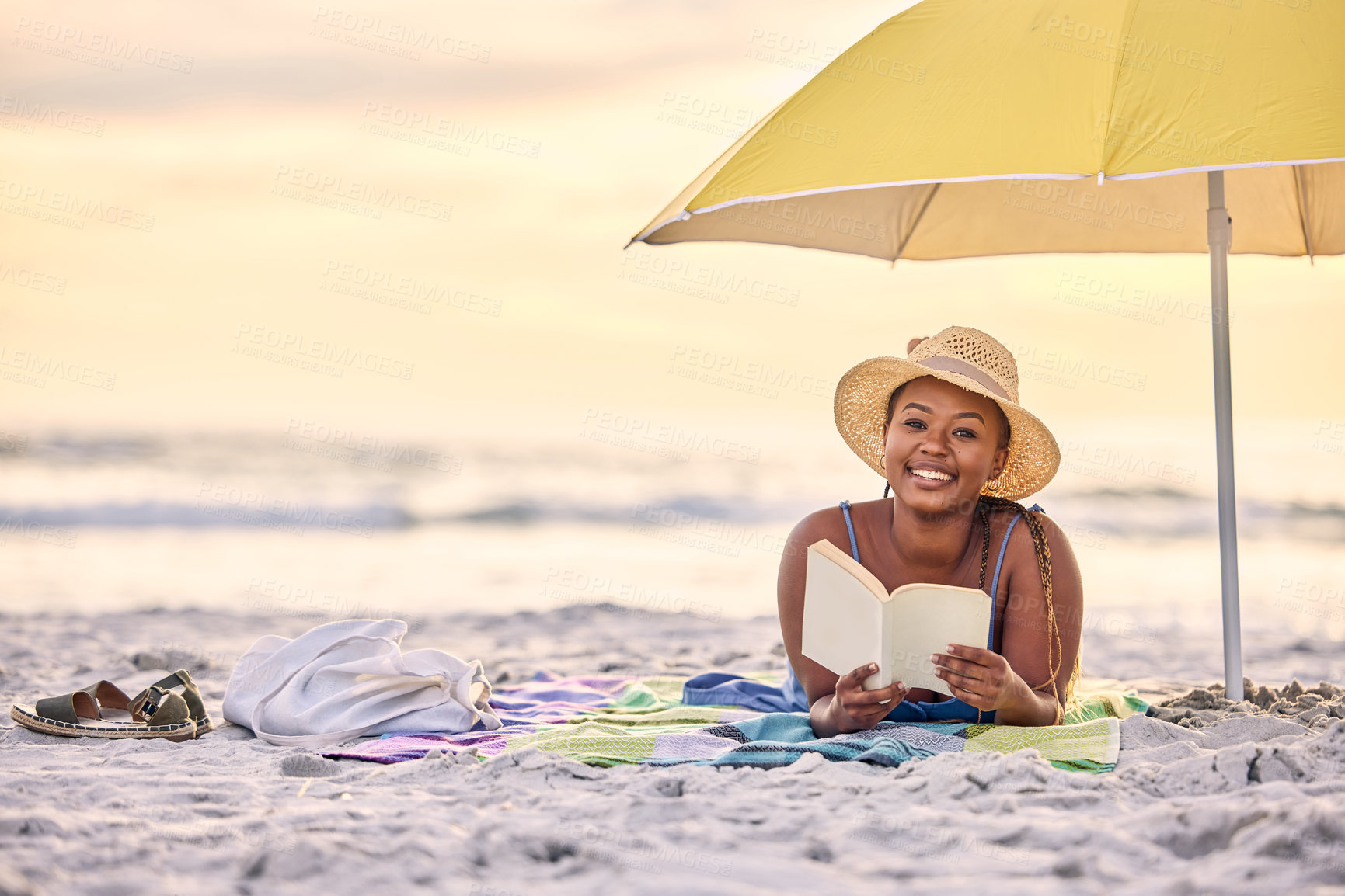 Buy stock photo Portrait of a beautiful young woman relaxing with a book at the beach