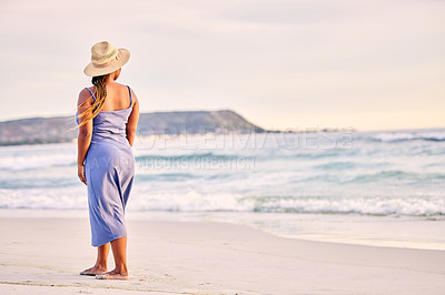 Buy stock photo Rearview shot of an unrecognizable woman walking along the beach