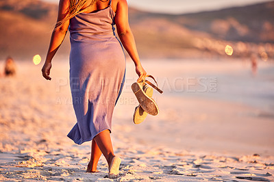 Buy stock photo Rearview shot of an unrecognizable woman walking along the beach