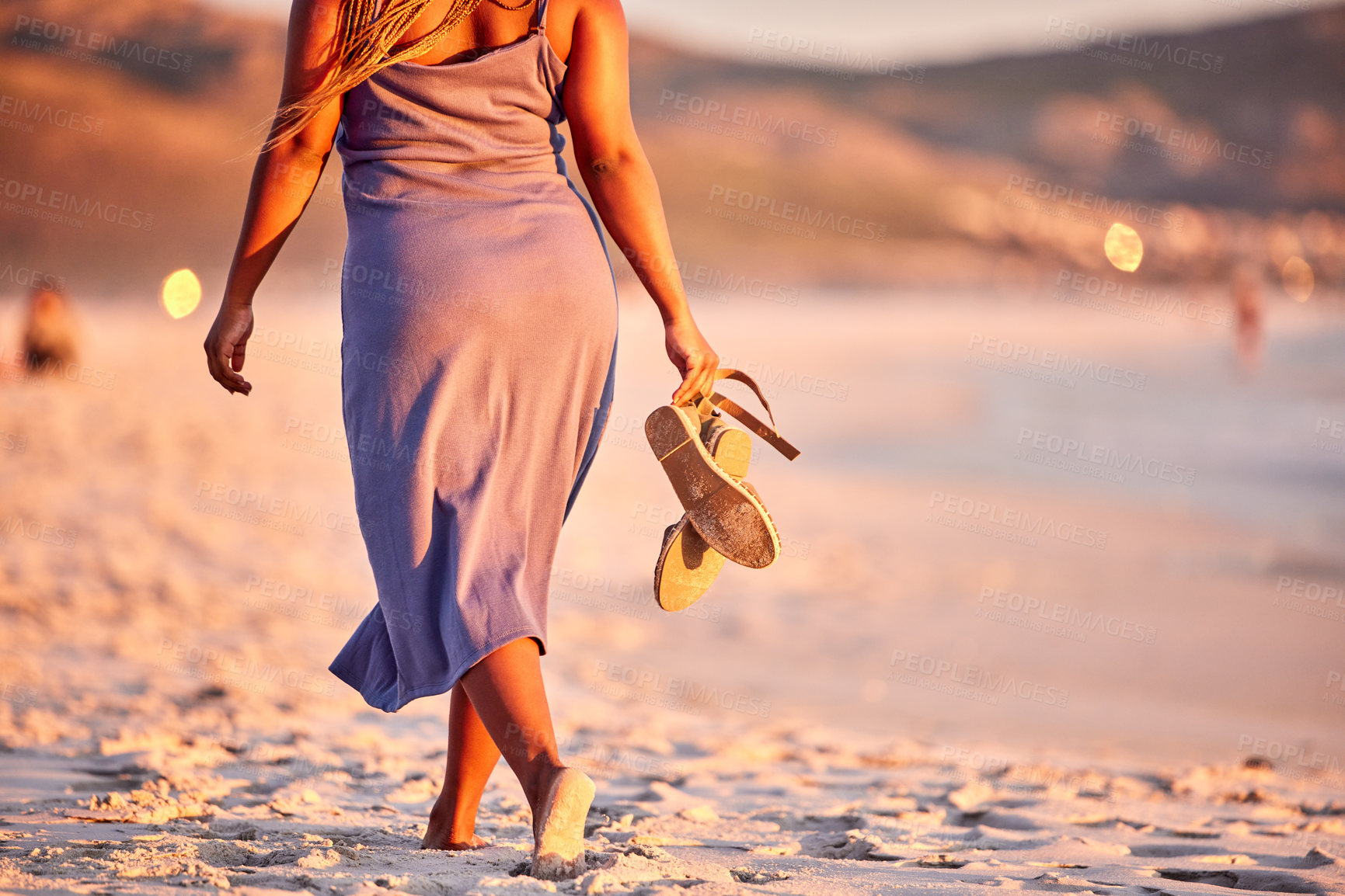 Buy stock photo Rearview shot of an unrecognizable woman walking along the beach