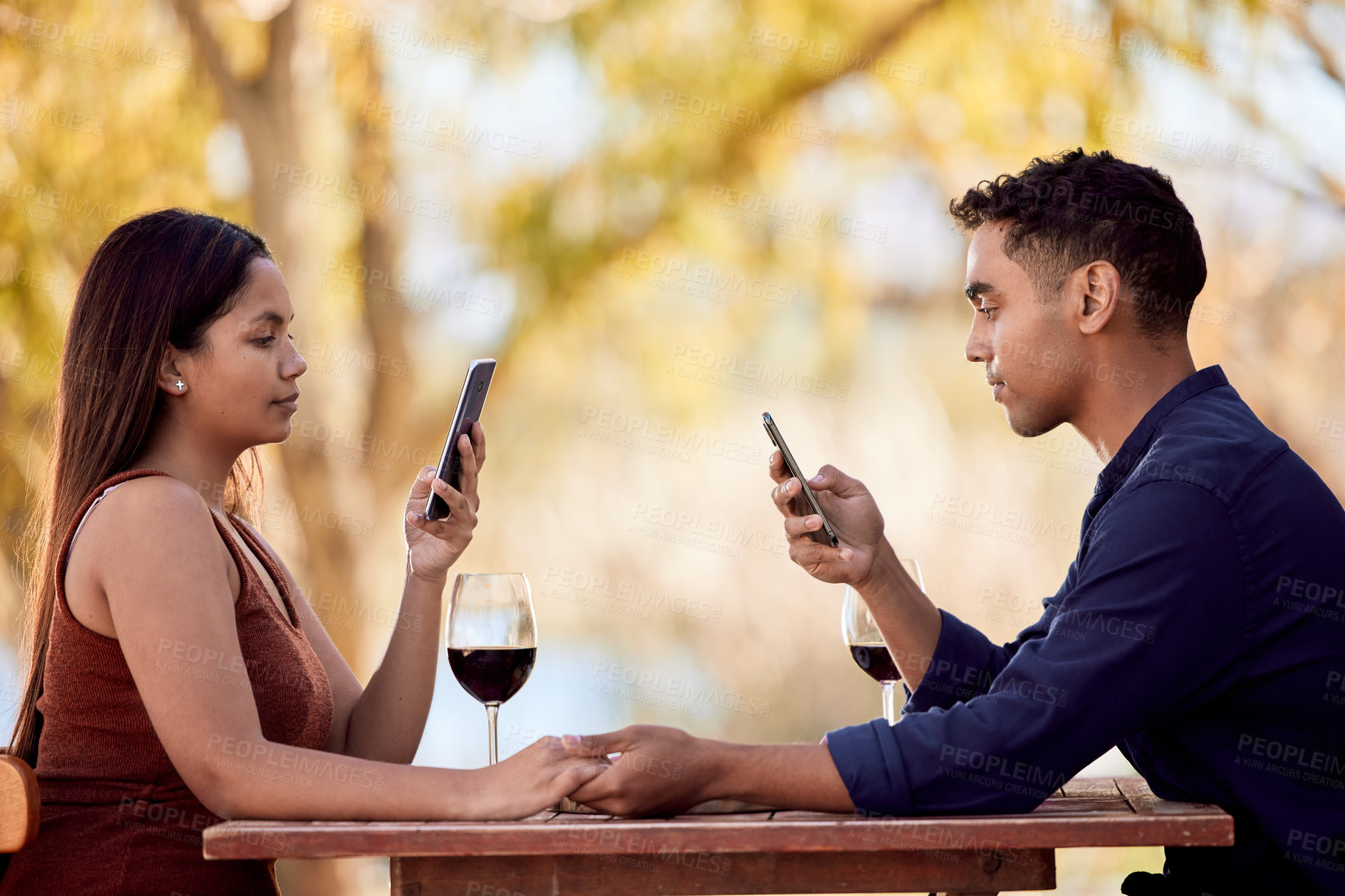 Buy stock photo Restaurant, date and couple reading with phone on social media, website and silence at dinner. Online, people and relax at cafe in summer on vacation, holiday and scroll internet holding hands