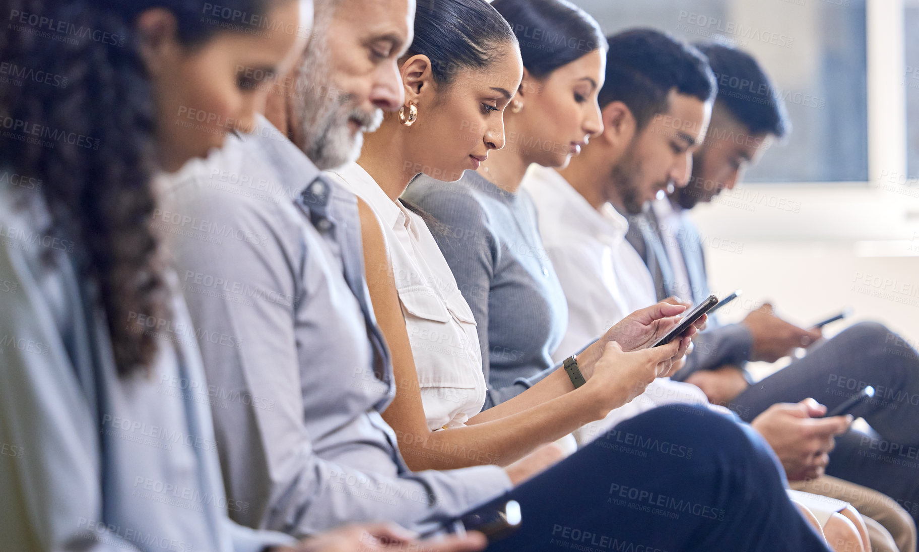 Buy stock photo Cropped shot of a group of businesspeople using their cellphones while sitting in the office during a conference