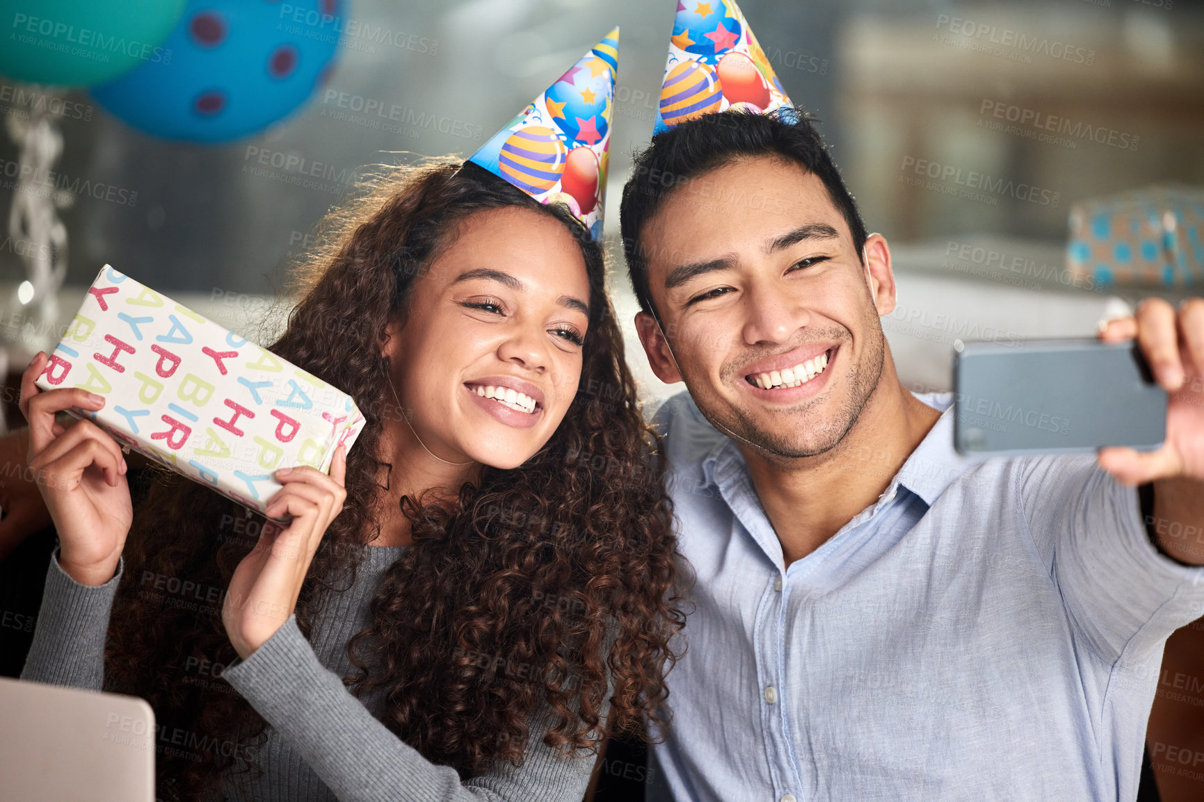 Buy stock photo Shot of two young businesspeople taking a selfie while celebrating a birthday at work
