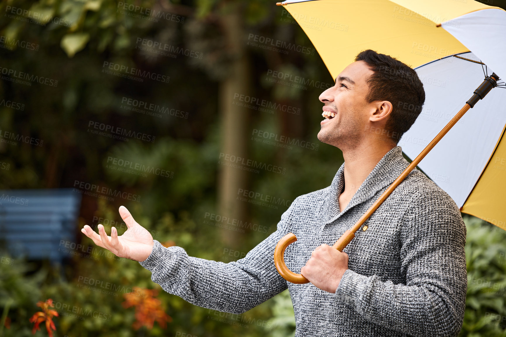 Buy stock photo Shot of a young man standing in the rain with an umbrella