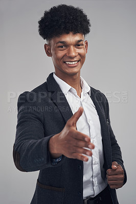 Buy stock photo Studio shot of a young businessman extending his arm for a handshake against a grey background