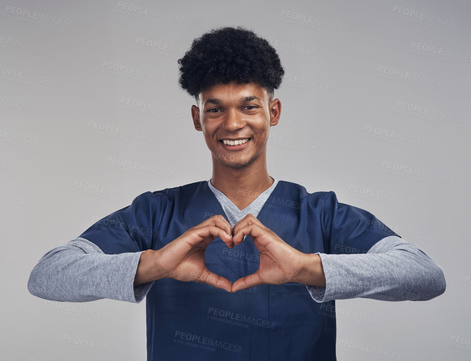 Buy stock photo Shot of a male nurse forming a heart shape with his hands while standing against a grey background