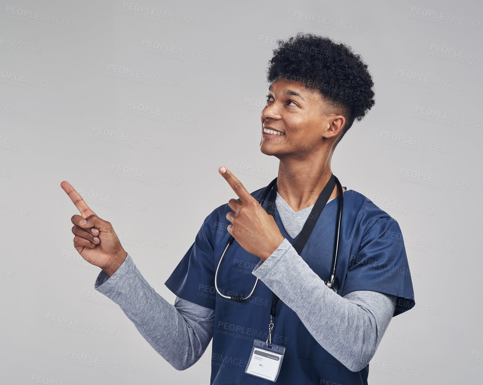 Buy stock photo Shot of a male nurse pointing at copy space while standing against a grey background
