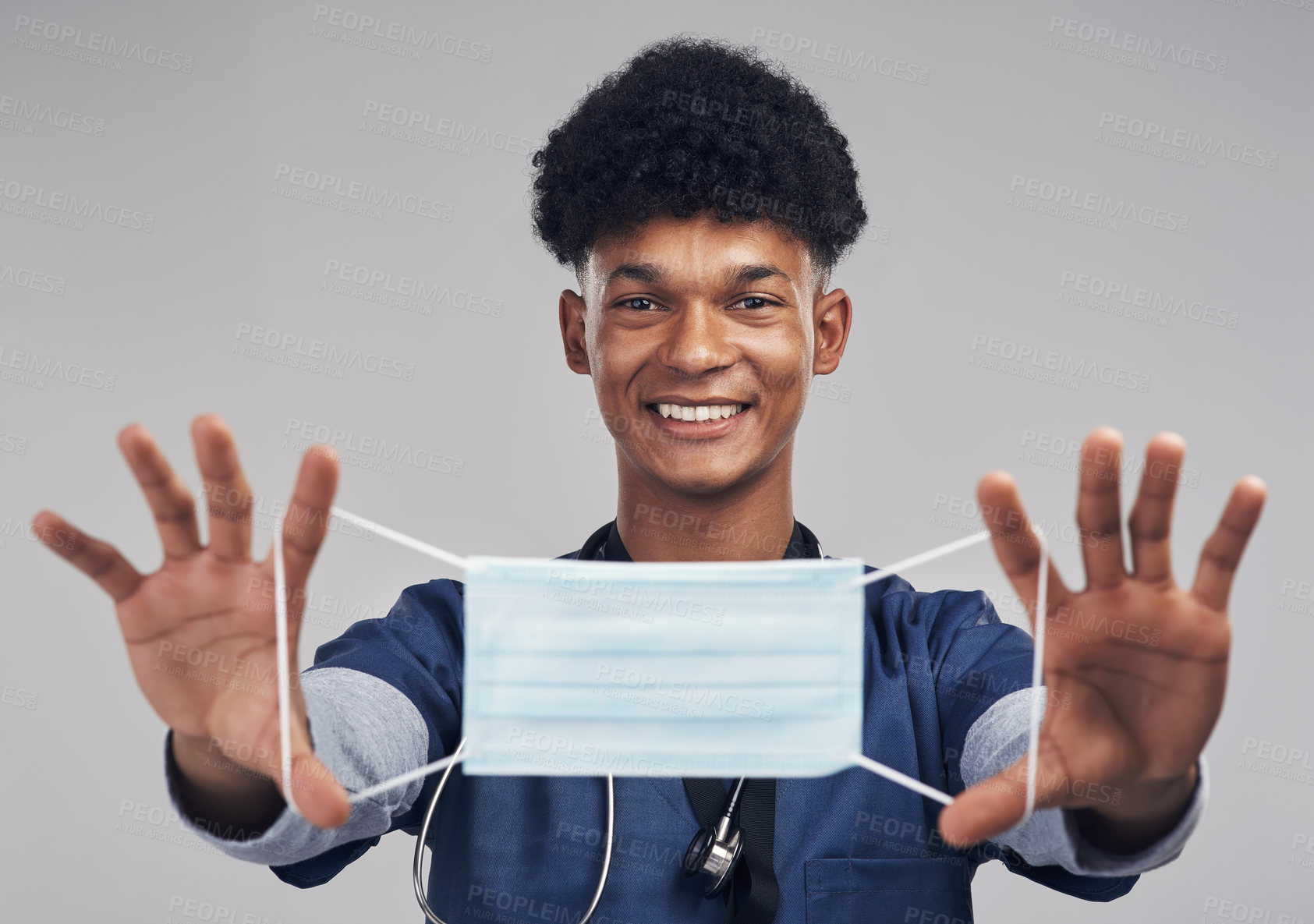 Buy stock photo Shot of a male nurse holding up a surgical mask while standing against a grey background