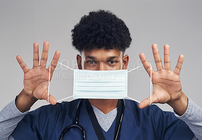 Buy stock photo Shot of a male nurse holding up a surgical mask while standing against a grey background