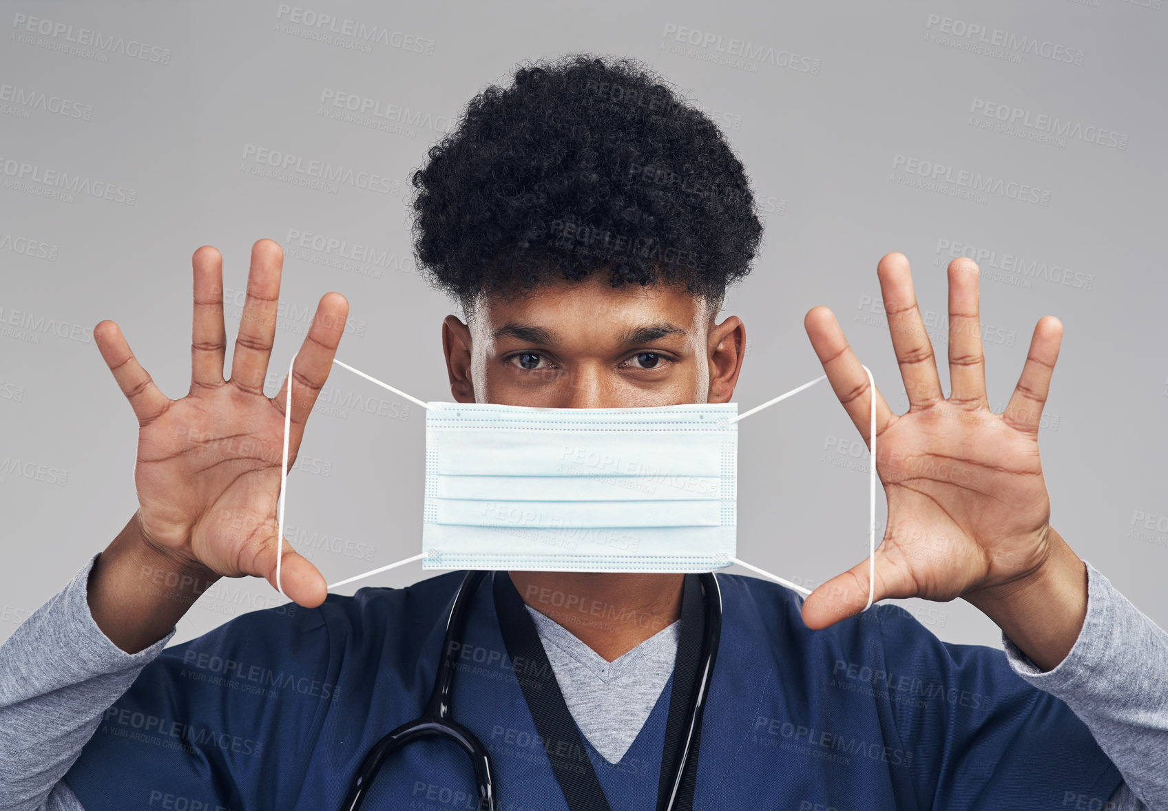 Buy stock photo Shot of a male nurse holding up a surgical mask while standing against a grey background