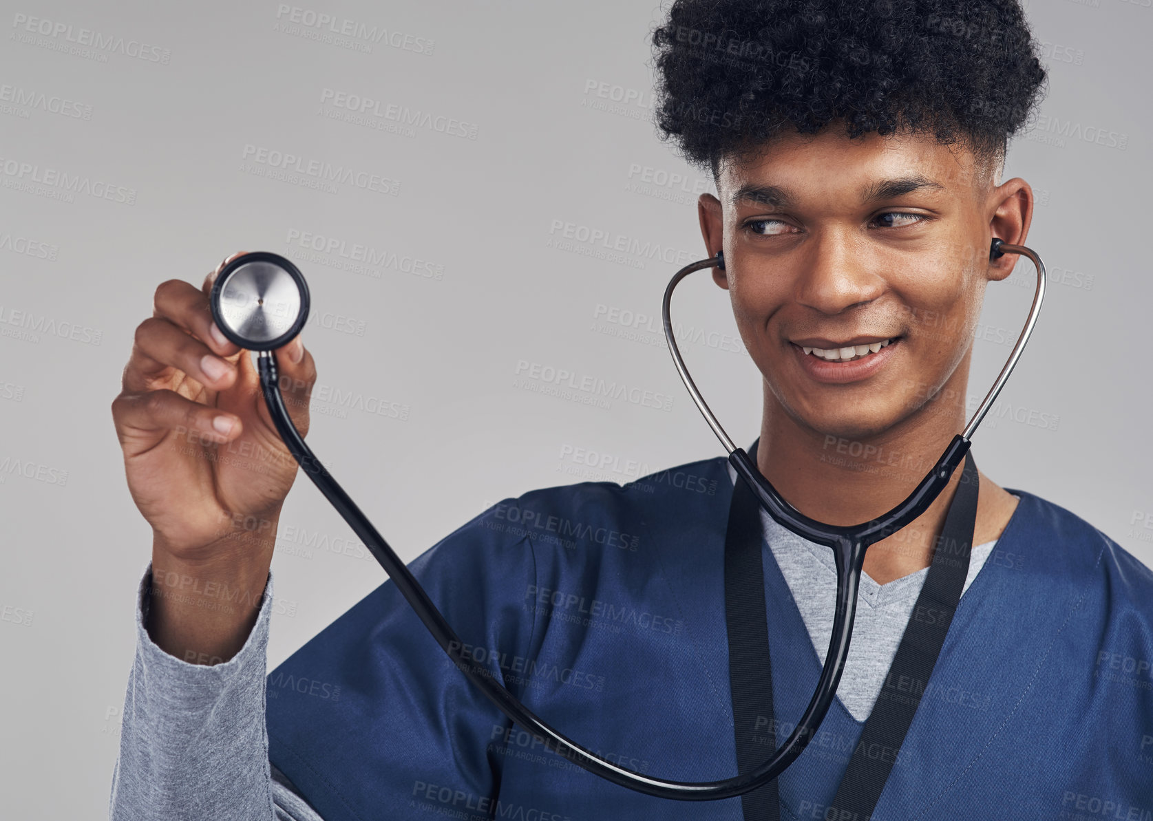 Buy stock photo Shot of a male nurse holding up a stethoscope while standing against a grey background