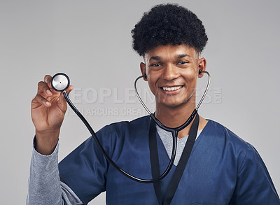 Buy stock photo Shot of a male nurse holding up a stethoscope while standing against a grey background