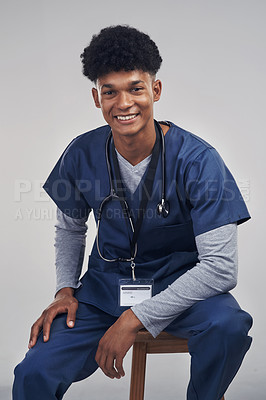 Buy stock photo Studio shot of a male nurse sitting on a chair against a grey background