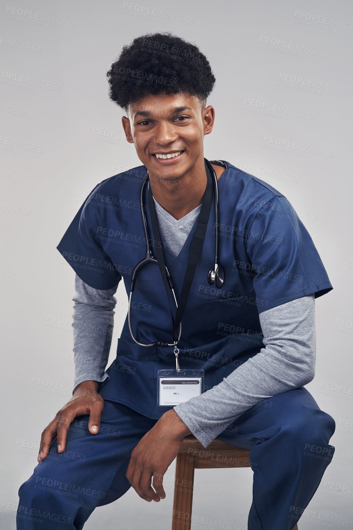 Buy stock photo Studio shot of a male nurse sitting on a chair against a grey background