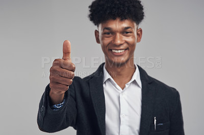 Buy stock photo Shot of a young man wearing a suit and showing thumbs up against a grey background
