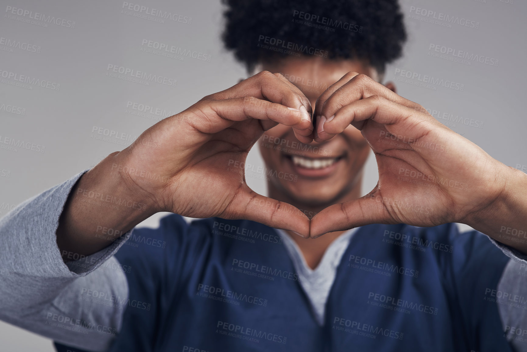 Buy stock photo Shot of a male nurse forming a heart shape with his hands while standing against a grey background