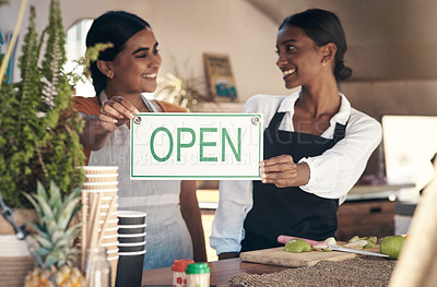Buy stock photo Shot of two young businesswomen holding an open sign in their food truck