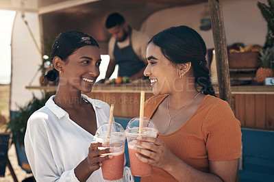 Buy stock photo Shot of two friends enjoying smoothies together
