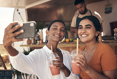 Buy stock photo Shot of two friends taking selfies while drinking smoothies