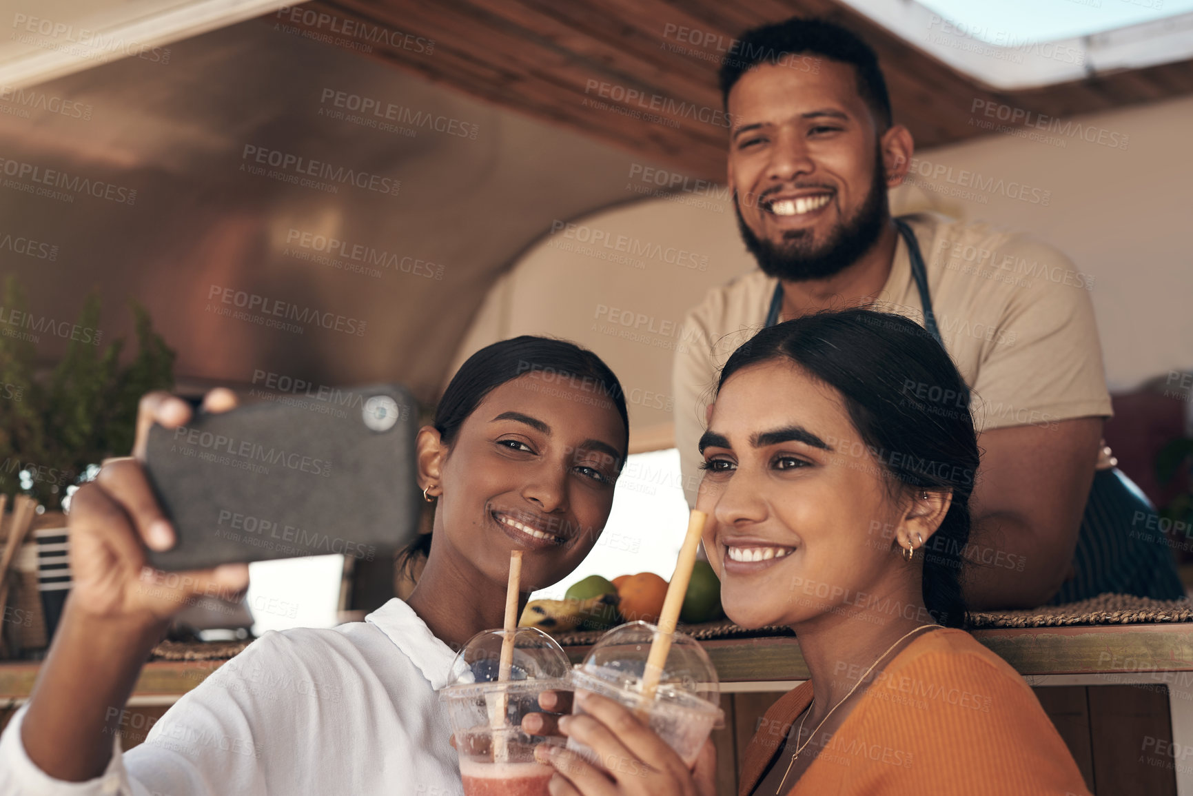 Buy stock photo Shot of two friends taking selfies while drinking smoothies