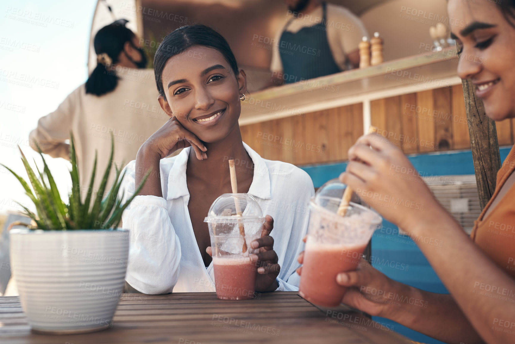 Buy stock photo Shot of two friends enjoying smoothies together