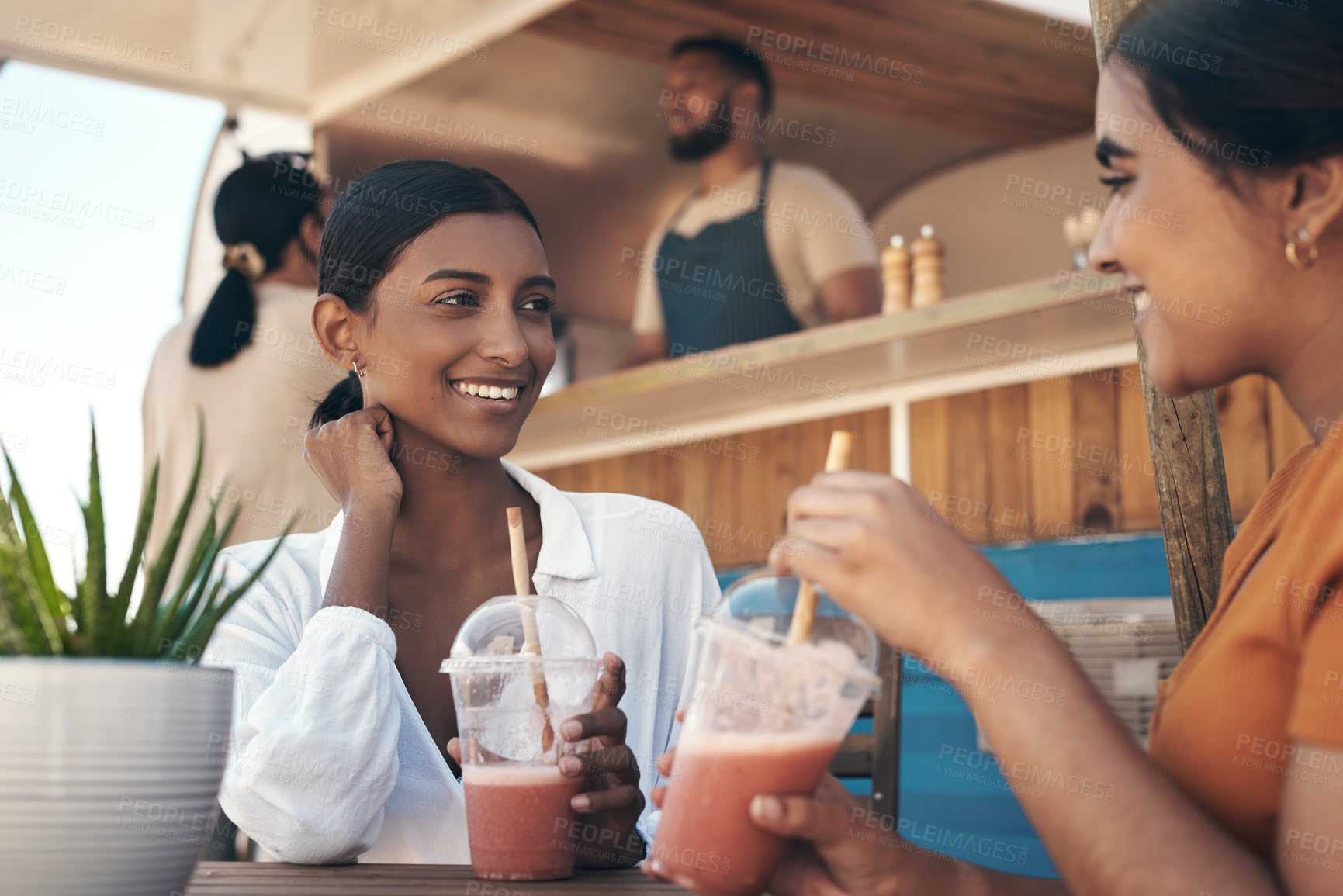 Buy stock photo Shot of two friends enjoying smoothies together