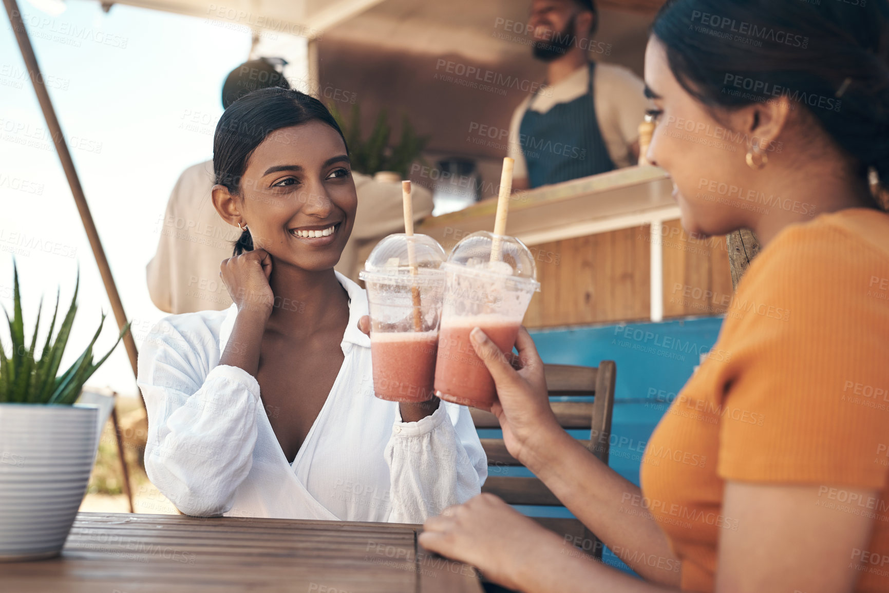 Buy stock photo Shot of two friends enjoying smoothies together